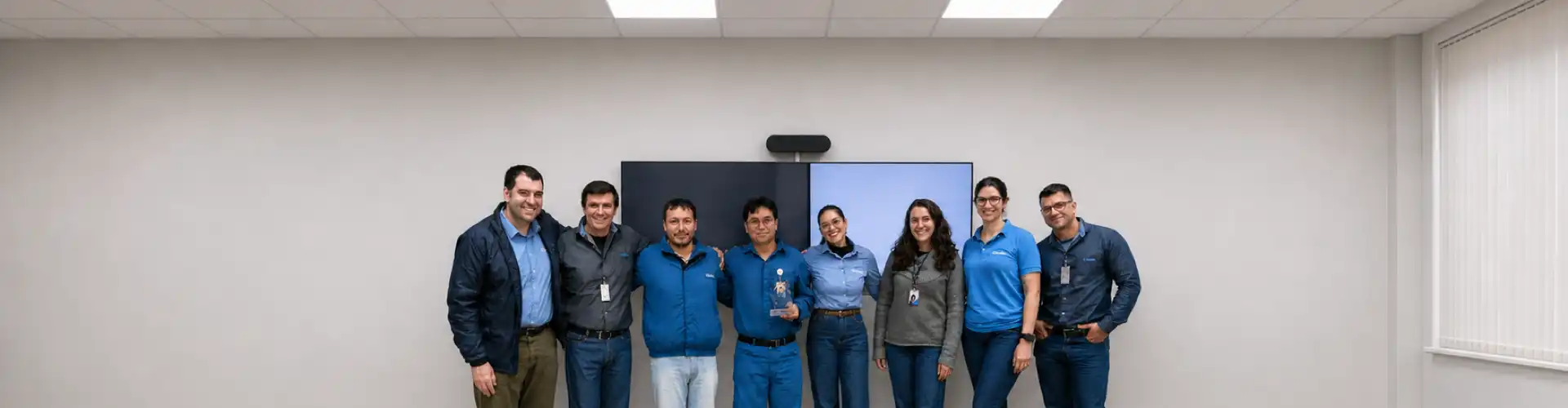 Equipes da Kurita e da Braskem PP4 reunidas em sala de reunião, com um troféu ao centro